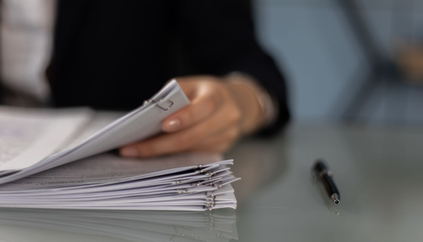 Professional arranging paper records beside a pen before document review
